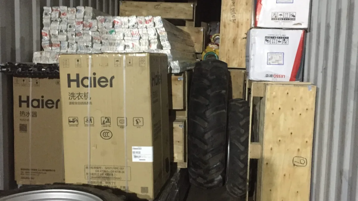 Mixed container with tractor tyres, home appliances and wooden crates