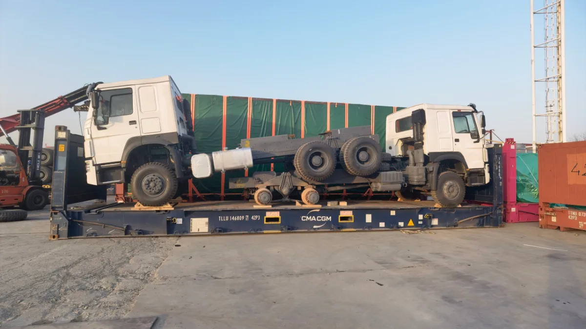Two trucks loaded on flat rack containers at a port yard