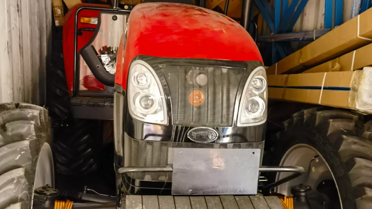 Worker loading a tractor into a shipping container